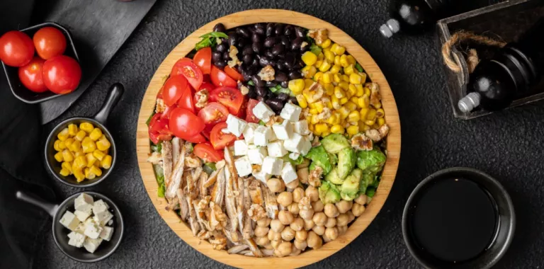 Plato de ensalada con tomates, frijoles negros, garbanzos, maíz y queso