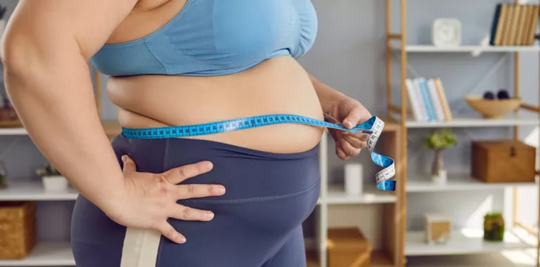 Mujer obesa utiliza cinta métrica para medir su perímetro abdominal