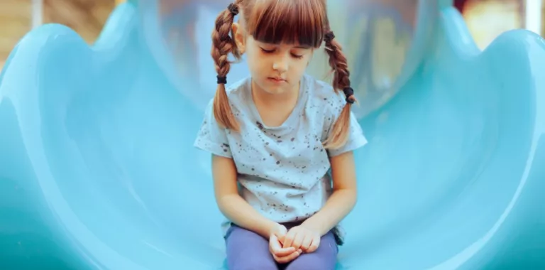 Niña pequeña sentada con expresión triste