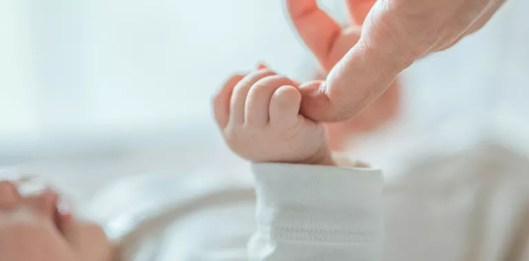 Bebé cogiéndole el dedo a su madre