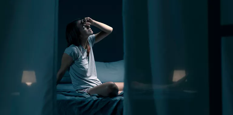 Mujer con sueño fragmentado se despierta en una habitación oscura