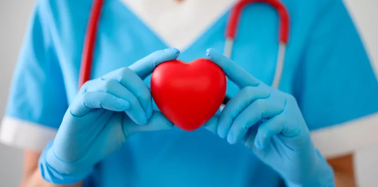 Médico sostiene un corazón rojo en sus manos