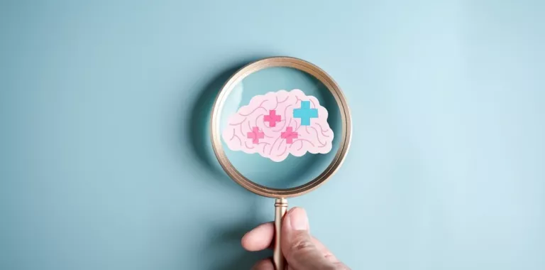 Una lupa enfoca un cerebro dibujado con signos de daño por ictus