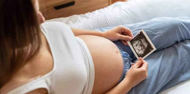 Embarazada tumbada mirando la ecografía de su futuro bebé