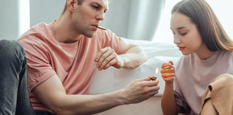 Hombre y mujer jóvenes se disponen a fumar cannabis