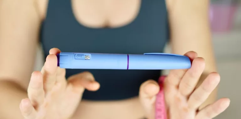 Mujer muestra una pluma de Ozempic y una cinta métrica Una mujer con ropa deportiva sujeta una pluma con semaglutida
