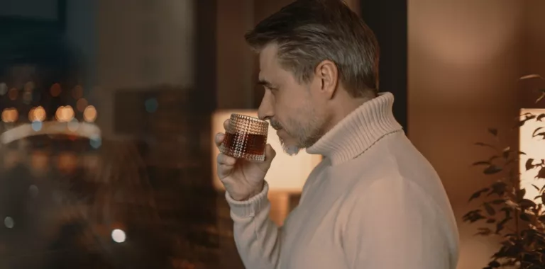 Hombre a punto de tomarse un whisky en su casa