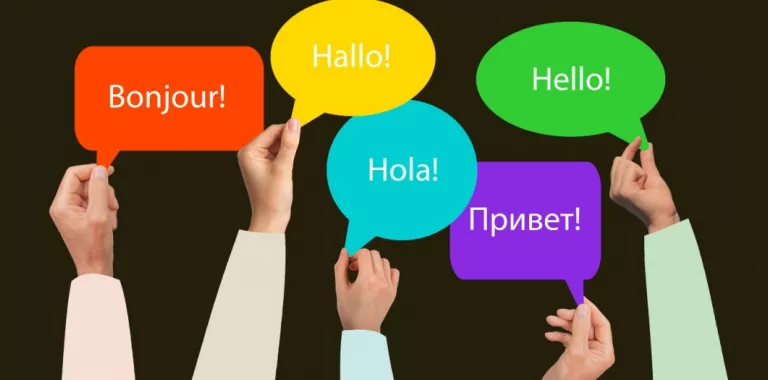 Varias manos sostienen carteles con un saludo en varios idiomas