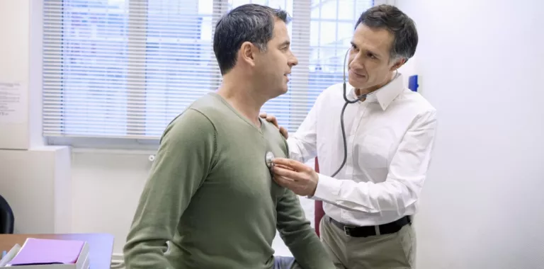 Doctor ausculta a un hombre para comprobar su función cardíaca Médico ausculta a un hombre
