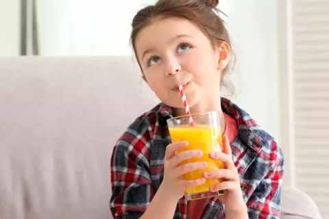 Niña bebiendo un zumo de naranja