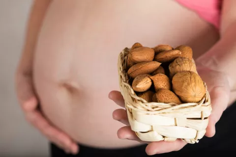 Beneficios de tomar frutos secos en el embarazo Embarazada sostiene frutos secos
