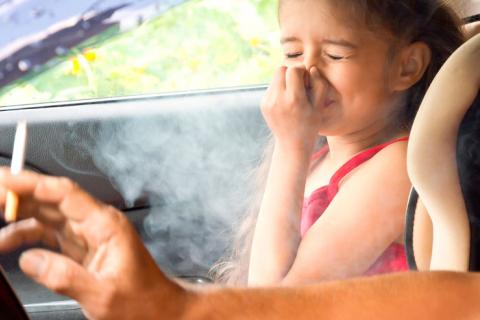 Persona fumando en el coche junto a su hija