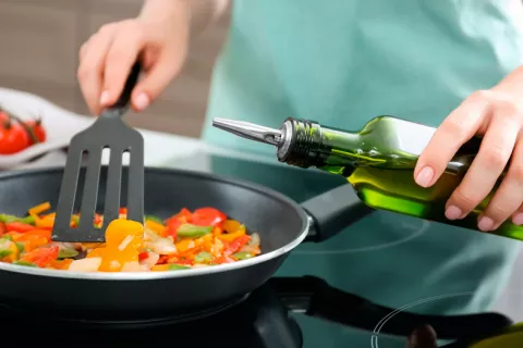 Mujer utilizando el aceite de oliva para freír