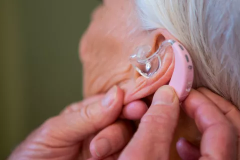 Llevar audífono reduce el riesgo de alzhéimer, depresión y caídas Mujer llevando audífono para reducir el riesgo de alzhéimer, depresión y caídas