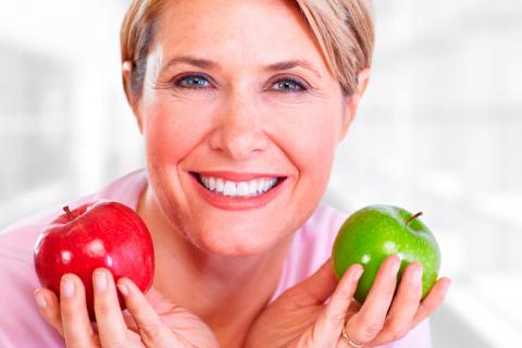 Mujer comiendo dos manzanas al día para tener menos obesidad