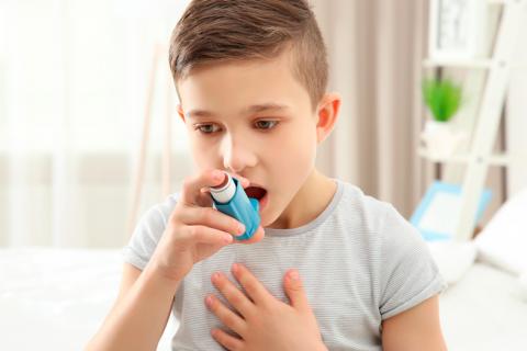 Niño asmético usando un inhalador 
