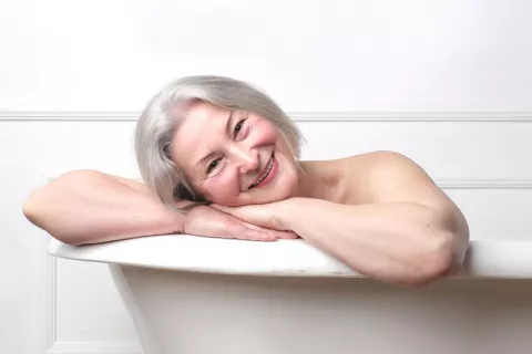 Un baño caliente a diario reduce el riesgo cardíaco y cerebrovascular Mujer mayor dándose un baño caliente para reducir el riesgo cardíaco