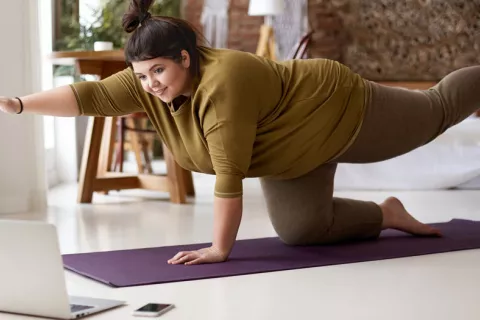 Hacer Pilates rebaja la presión arterial en mujeres jóvenes y obesas Mujer con obesidad realizando pilates en casa