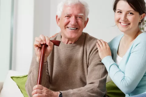 Un anciano y su cuidadora sonriendo