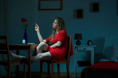 Mujer con insomnio fumando junto a la cama
