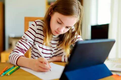 Los niños que escriben a mano aprenden más y recuerdan mejor Niña escribiendo a mano y haciendo sus tareas escolares