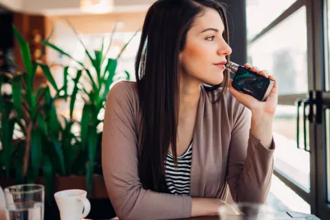 Las personas que vapean son más proclives a sufrir niebla mental Chica vapeando en una cafetería
