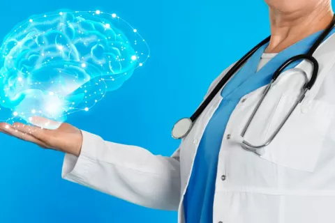 Hallan un gen cuya alteración afecta al aprendizaje y la memoria Médico sosteniendo una infografía de un cerebro