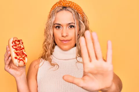 Pequeños cambios en la dieta permiten ganar minutos de vida saludable Mujer joven rechazando un hot dog