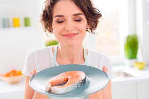 Mujer cocinando una rodaja de salmón