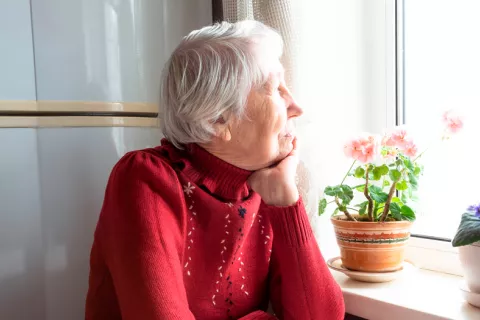 Haber pasado el COVID puede elevar el riesgo de párkinson Mujer mayor tras haber superado el COVID mira por la ventana