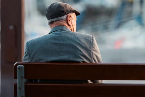 Anciano solitario sentado en un banco de la calle