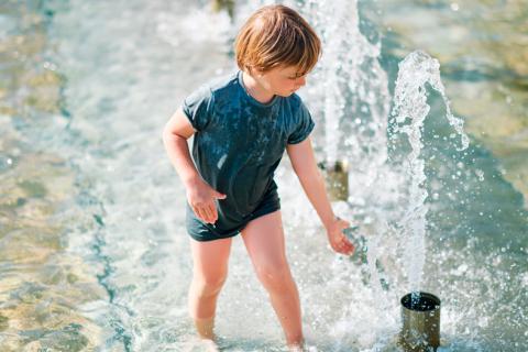 Niño mojándose en chorros de agua por la de calor
