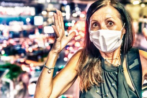 Mujer con mascarilla anticontaminación, horrorizada por el tráfico de la ciudad