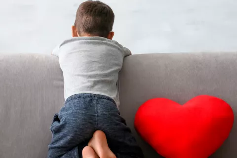 Niño sentado de espaldas en un sofá de casa.