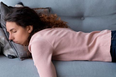 Mujer tumbada en el sofá agotada por el cansancio