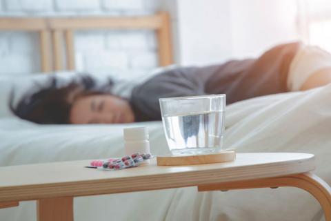 Mujer dormida junto a un vaso de agua y pastillas