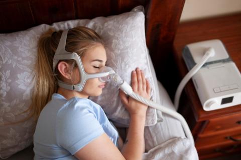 Mujer rubia con máquina de apnea del sueño para dormir