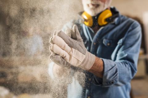 Trabajador con polvo desprendiéndose de sus guantes