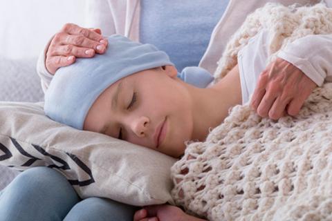 Niño con leucemia durmiendo sobre las piernas de su madre