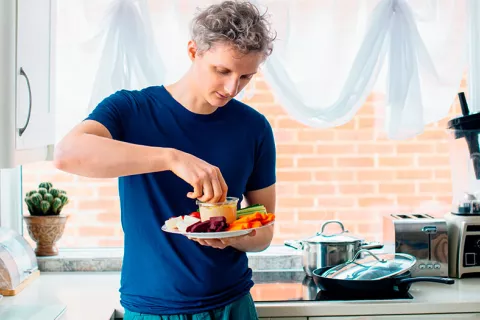 Hombre joven comiendo una ensalada mediterránea