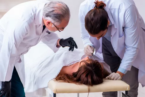 Dos médicos forenses examinando un cadaver