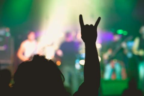 Una persona realizando el gesto de los &#039;cuernos del diablo&#039; en un concierto de heavy metal