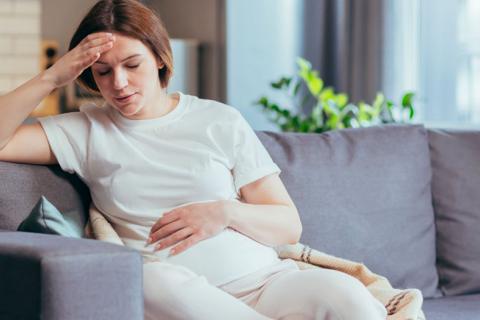 Embarazada con síntomas de ansiedad sentada en el sofá