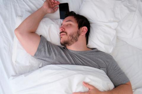Varón dormido junto a su teléfono móvil