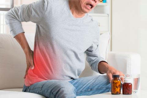 Persona tomando analgésicos para aliviar el dolor lumbar