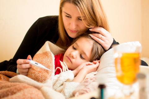 Madre tomando la temperatura a su hija enferma de gripe