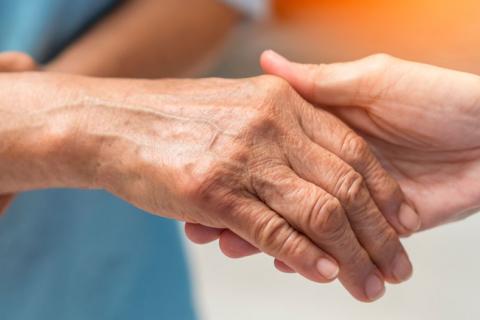Enfermera le da la mano a un paciente con enfermedad de Parkinson
