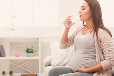 Mujer embarazada bebiendo un vaso de agua
