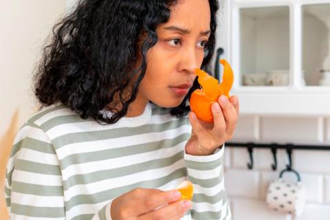 Mujer sin olfato intentando oler una naranja