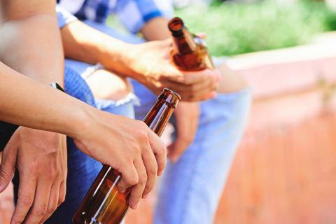 Dos amigos sentados con cervezas en la mano.